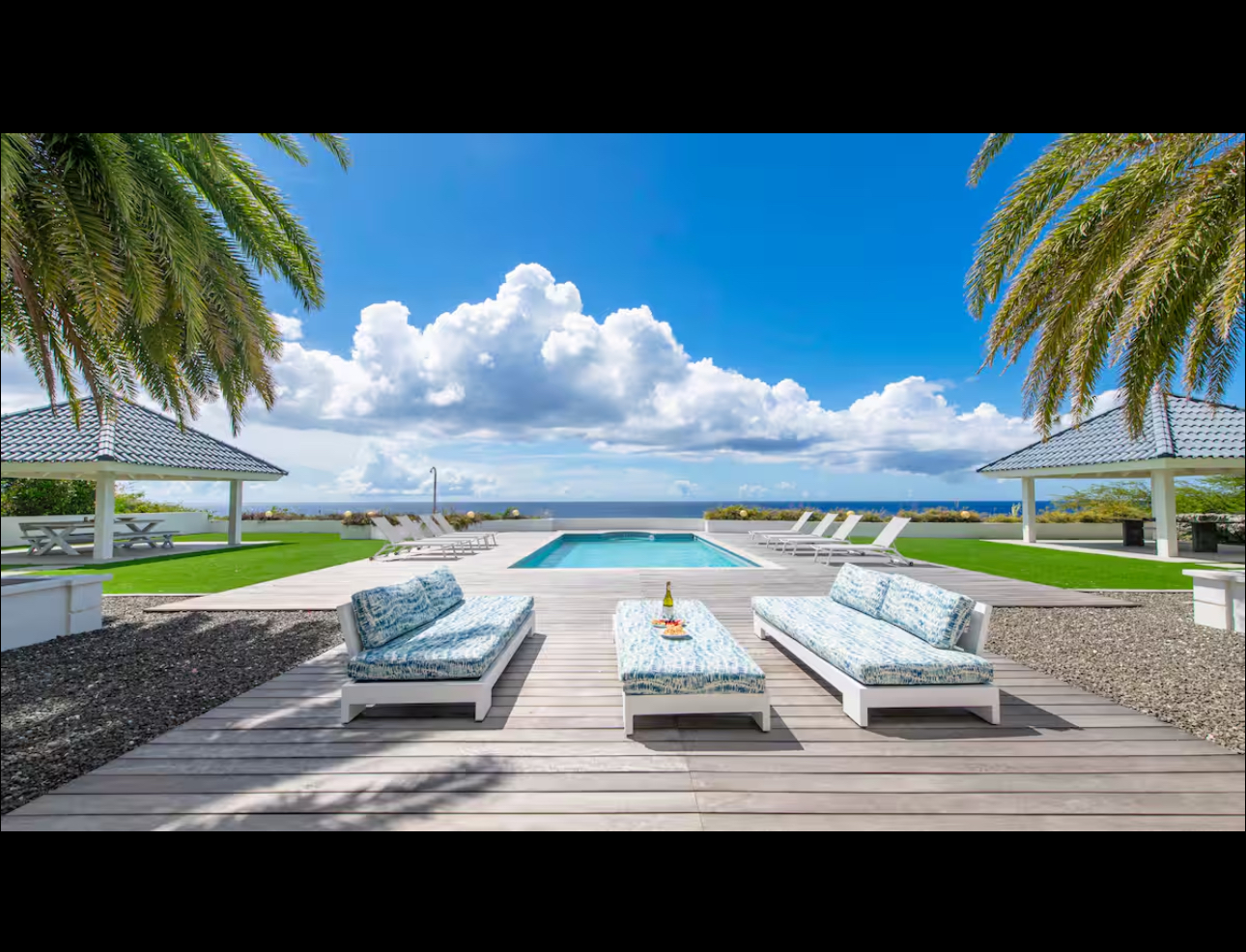 Ocean-facing pool deck with shaded lounge pavilions
