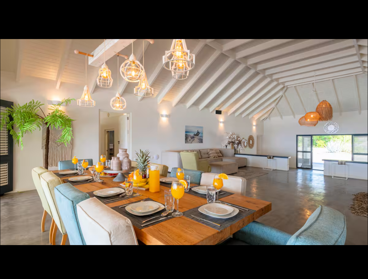 Long dining table set beneath sculptural pendant lights